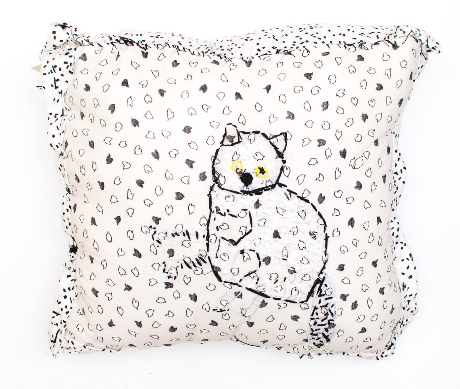 Textile artwork: white fabric pillow with black line drawing of seated cat and scattered teardrop pattern