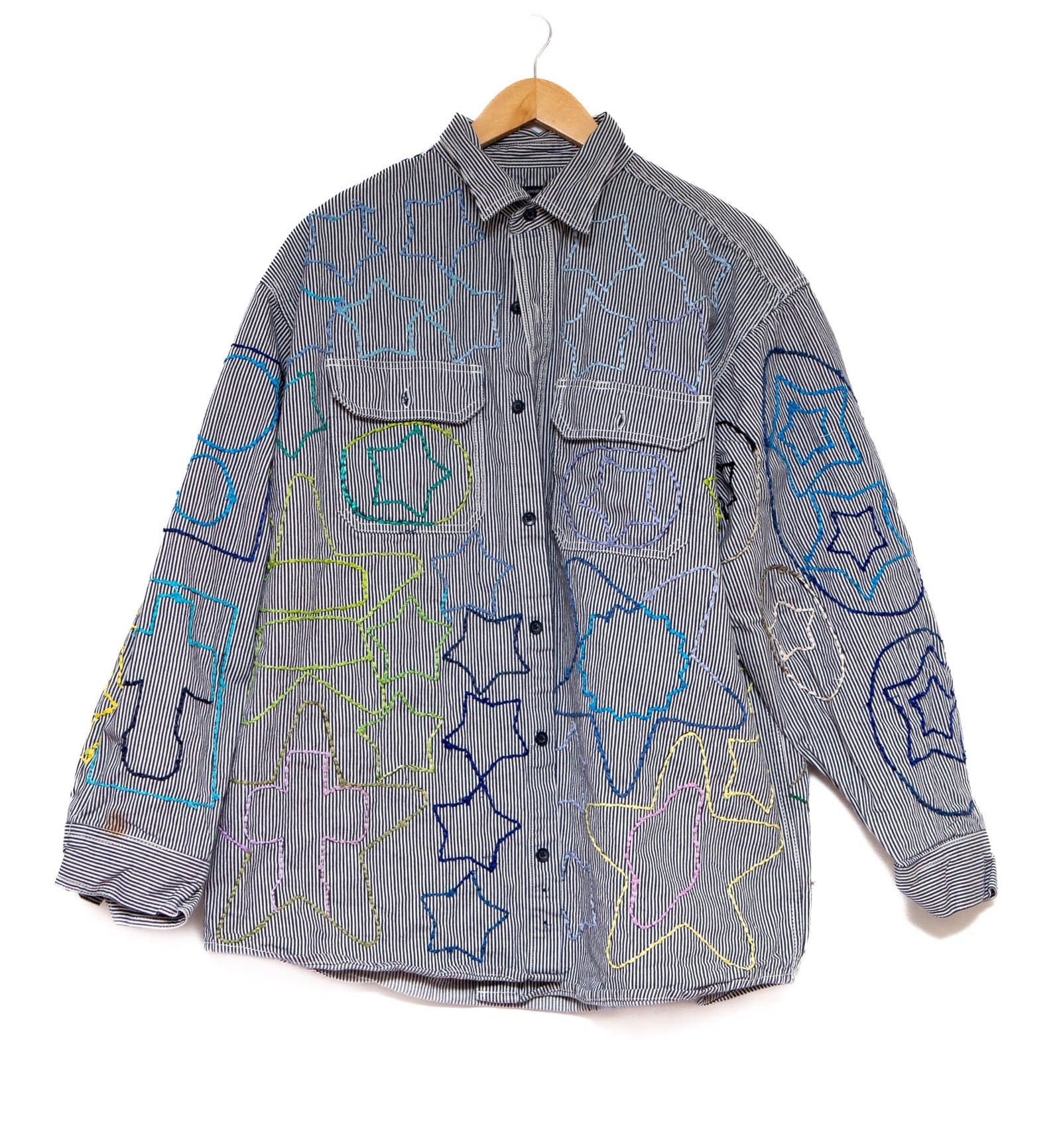 Textile artwork featuring a pinstriped dress shirt decorated with colorful embroidered text and symbols on fabric
