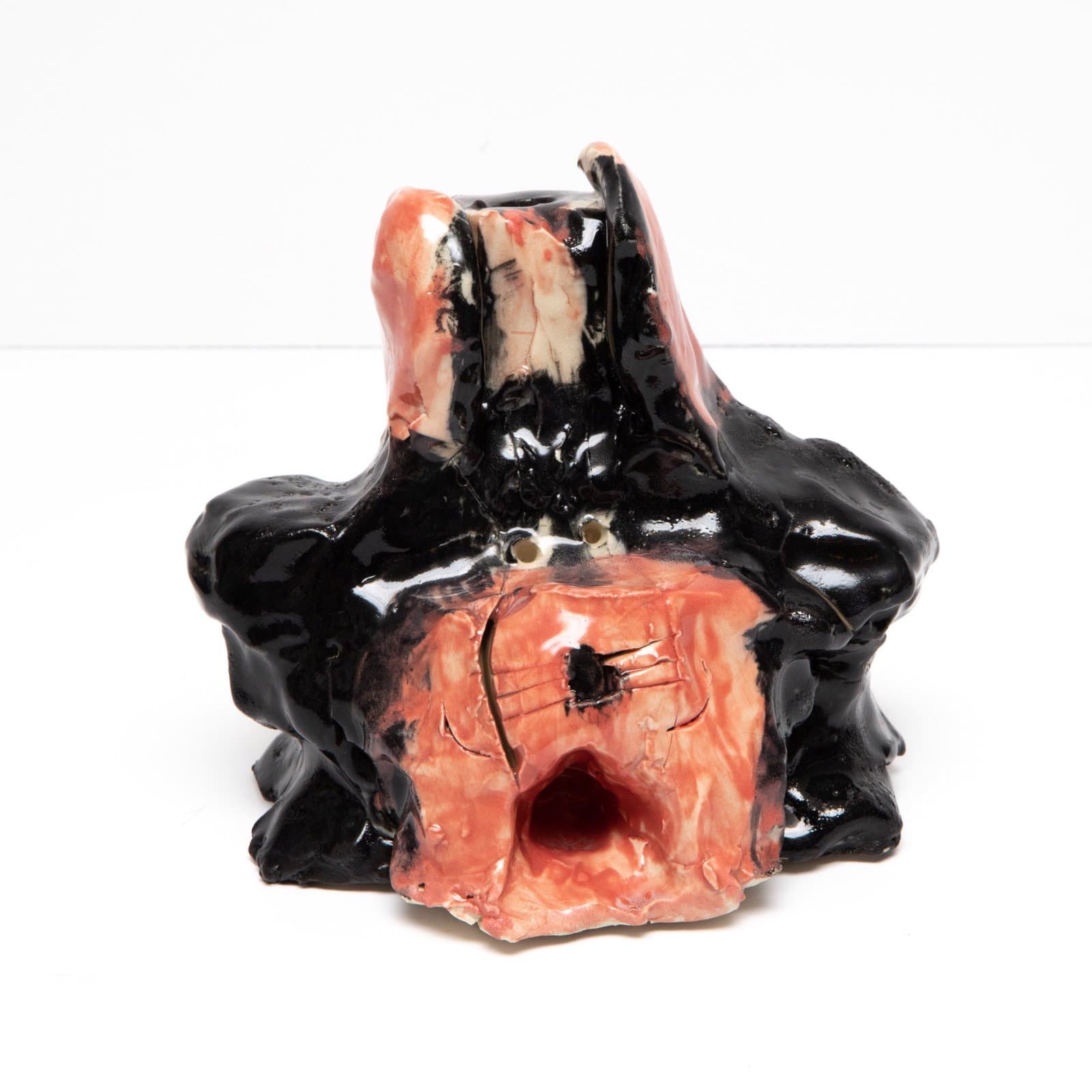Ceramic sculpture with glossy black glaze draping over coral-pink form with circular opening in front.