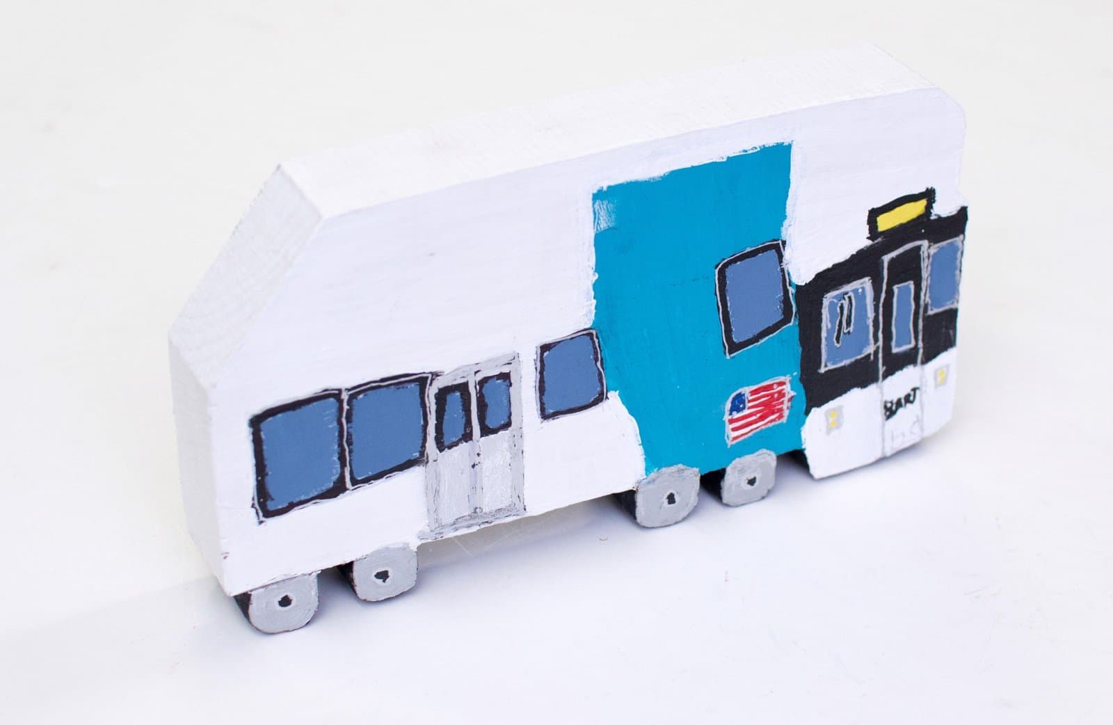 Handmade cardboard model train with white cars, blue center section, and American flag decal