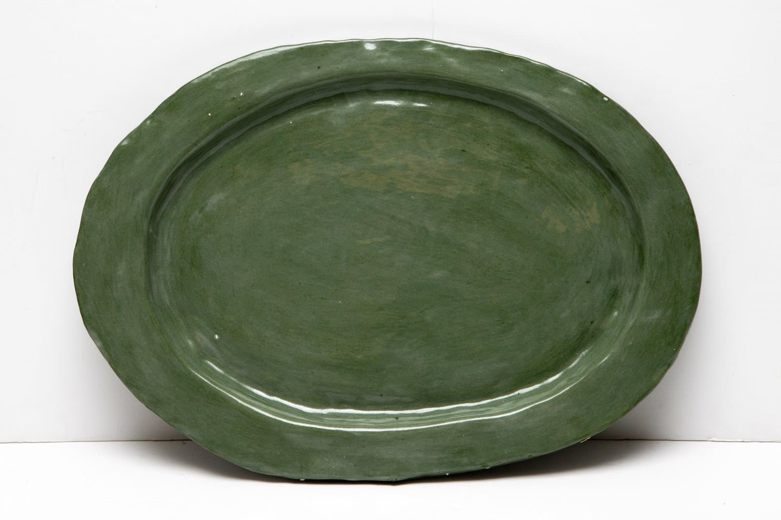 Large oval ceramic platter with deep green glaze featuring concentric ridged patterns on white background.