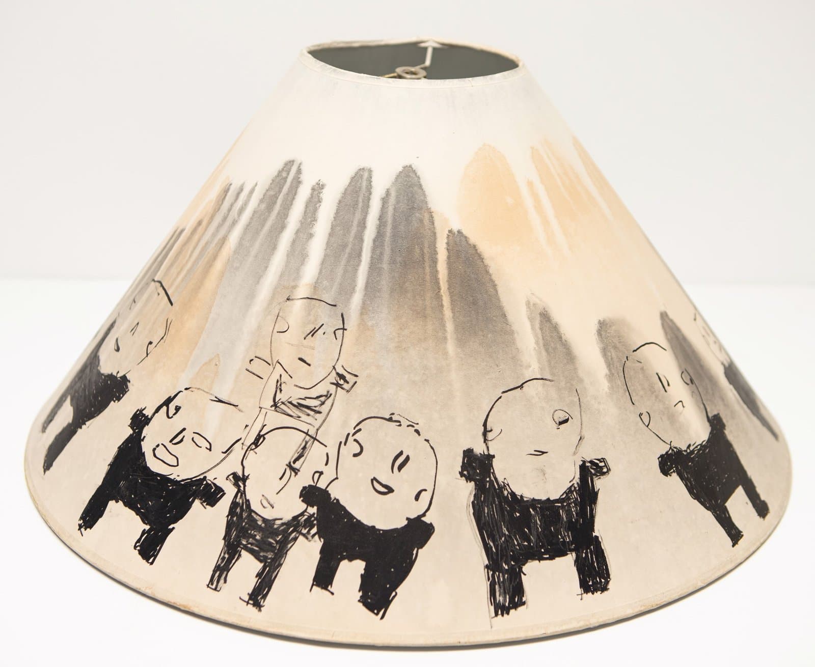 Ceramic lamp shade with hand-drawn figures in black ink and watercolor washes on cream-colored surface.