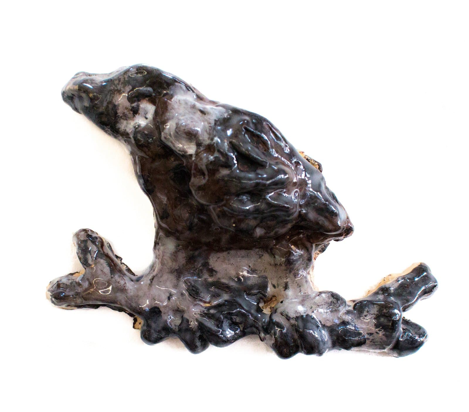 Ceramic sculpture of a bird perched on a branch, glazed in deep black and pale gray tones.