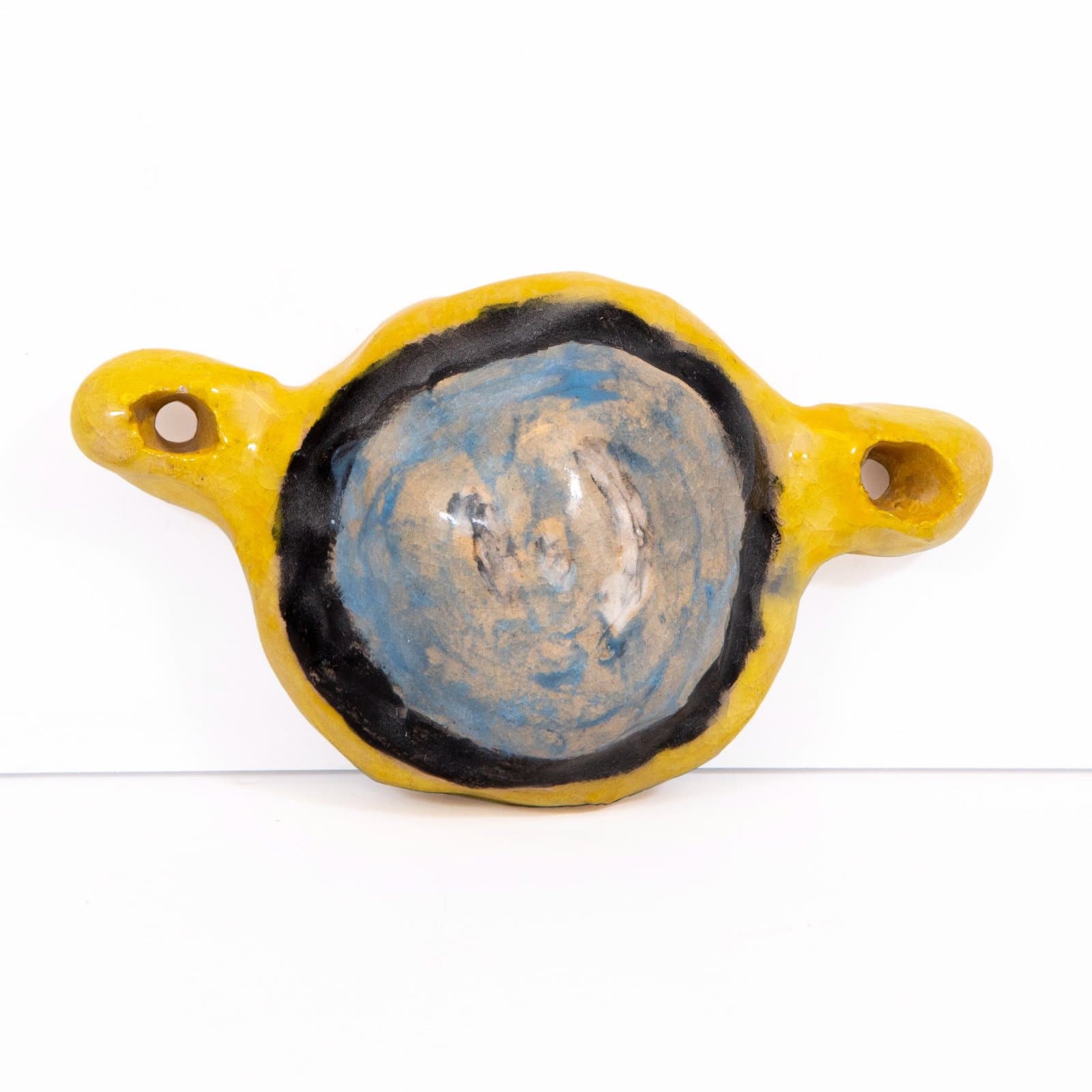 Ceramic vessel with bright yellow exterior, black rim, and swirled blue-tan glazed interior