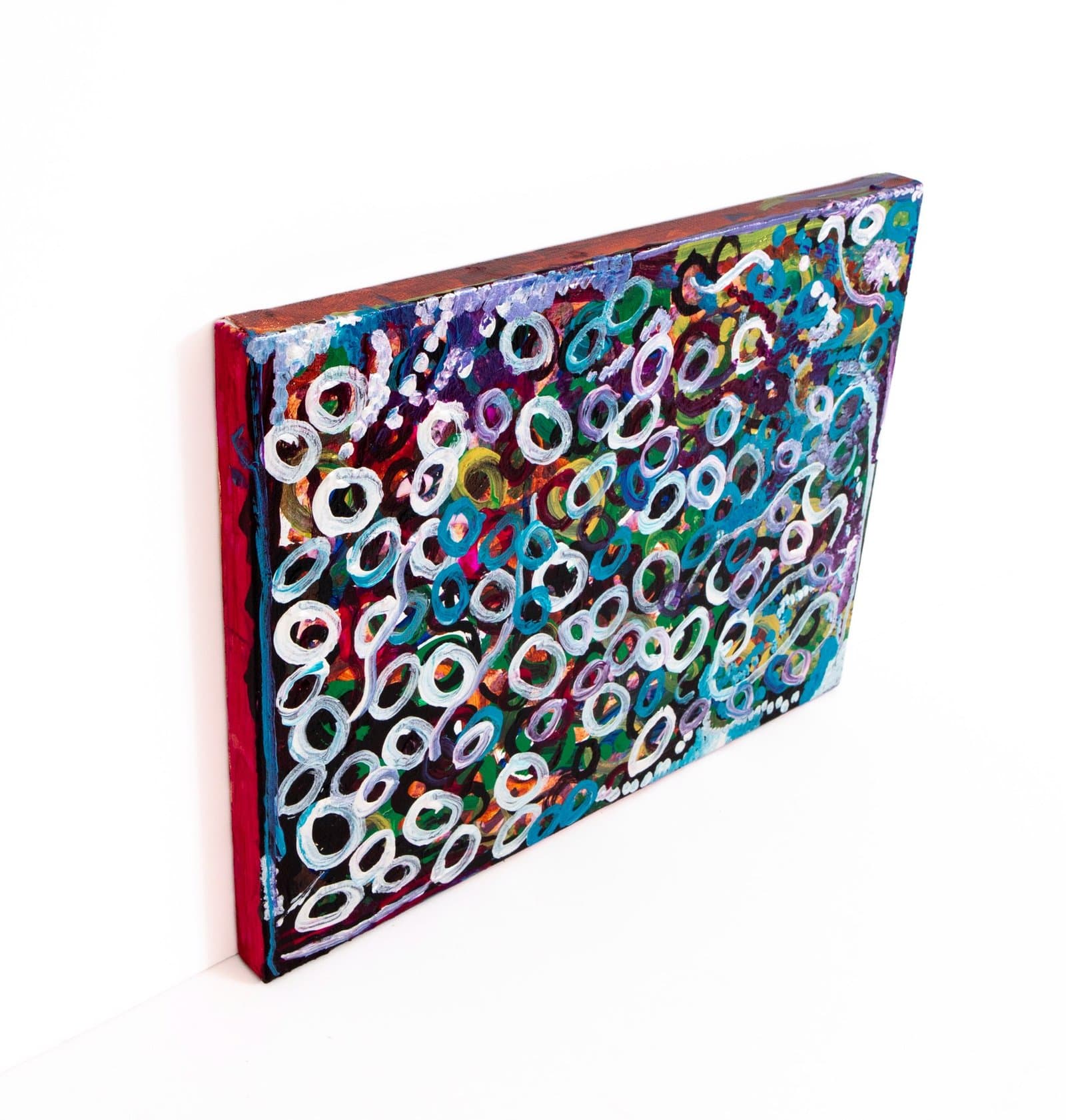 Abstract acrylic painting with densely packed white circular forms overlapping multicolored background on canvas.