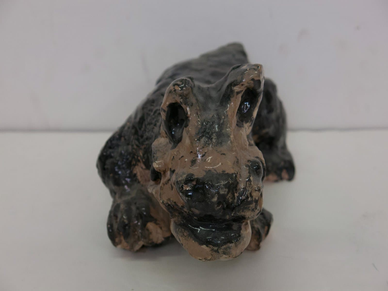 Ceramic sculpture of a crouching toad or frog with mottled brown and dark green glazed surface