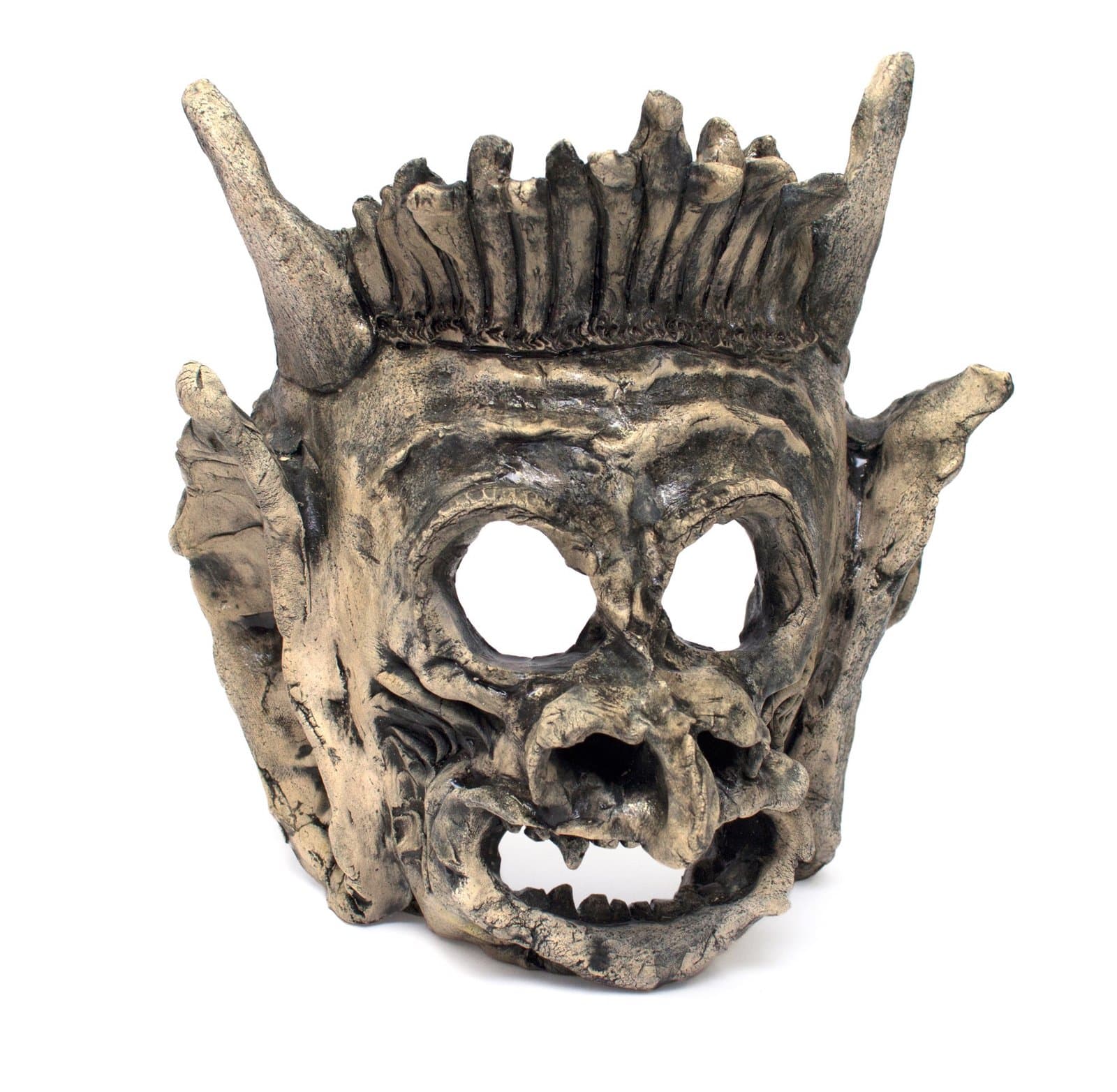 Ceramic mask sculpture with horned crown, hollow eye sockets, and open mouth showing teeth in mottled brown clay.