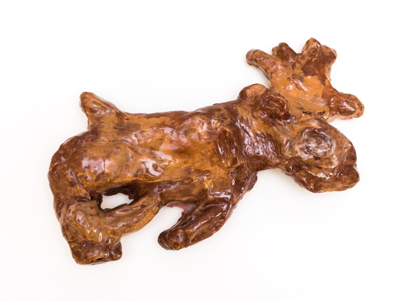Ceramic sculpture of a brown glazed figure in reclining pose with crown-like protrusion from head
