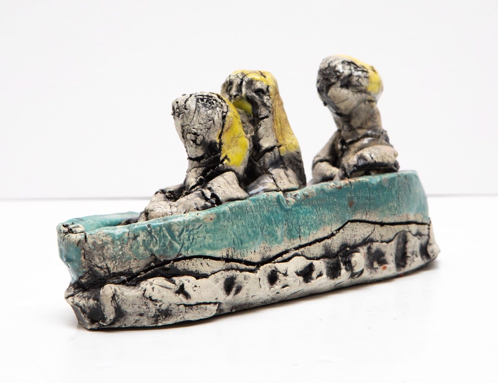 Ceramic sculpture with two seated figures on a turquoise glazed base with gray and black marbled surface decoration.