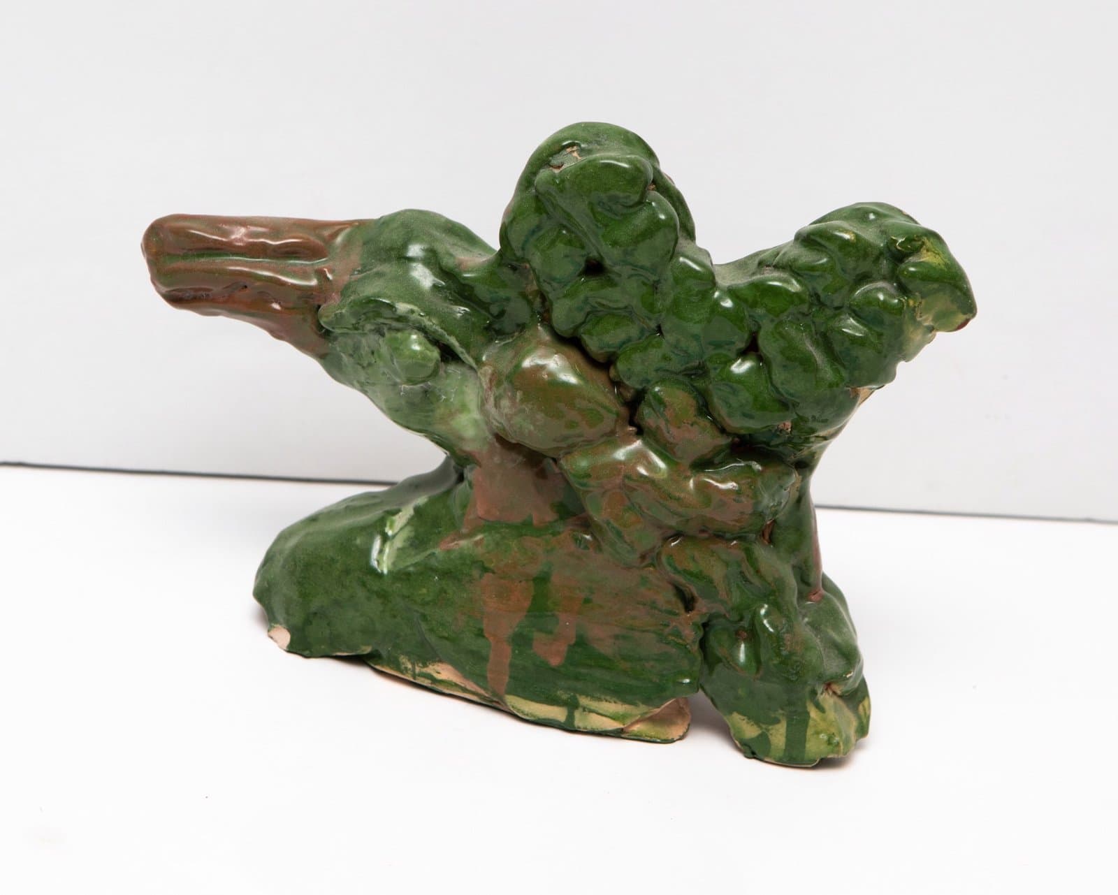 Ceramic sculpture with organic, bulbous forms in green glaze with brown undertones on white background.