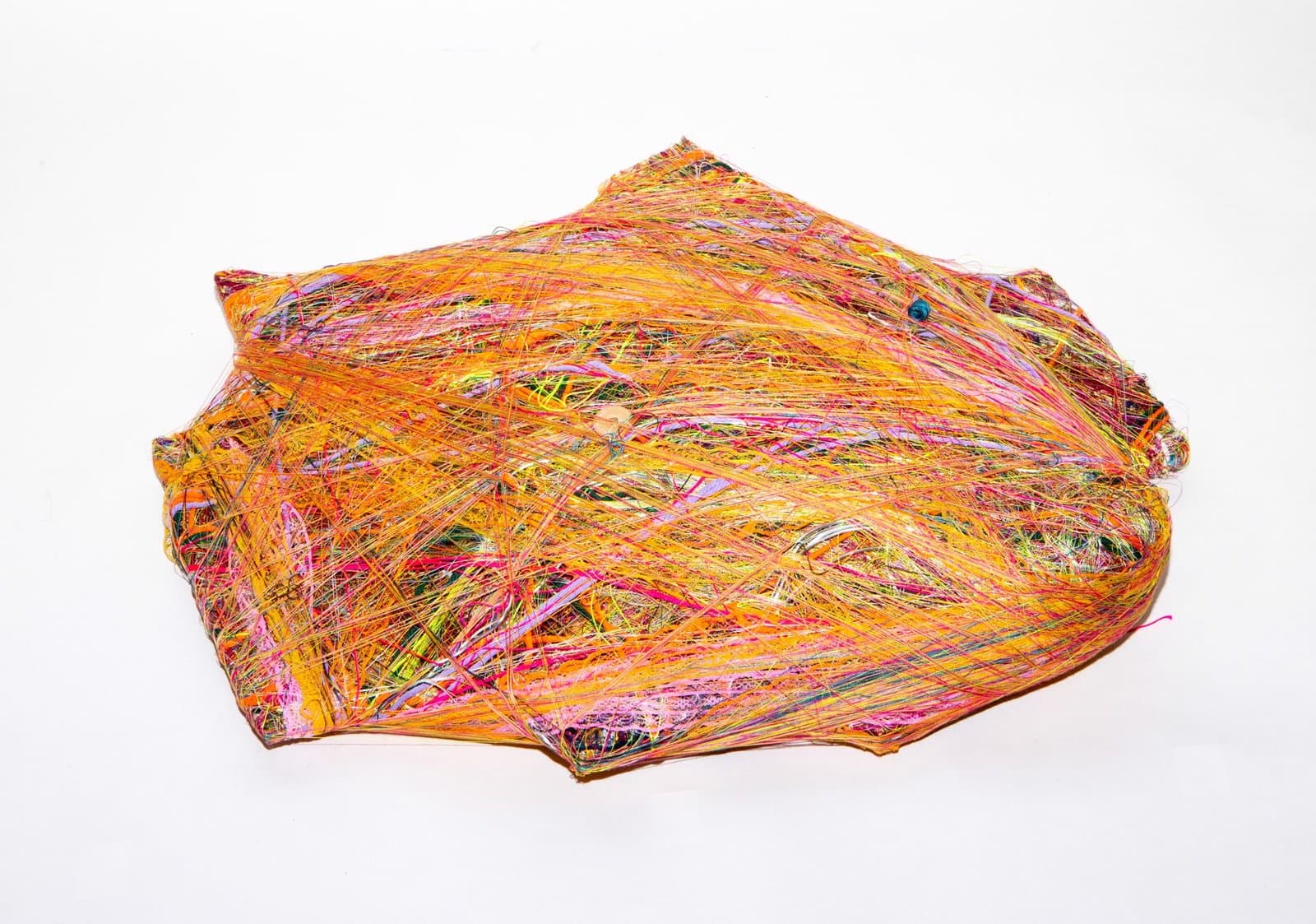 Wrapped sculpture with dense multicolored thread covering an irregular form in orange, pink, yellow, and purple.