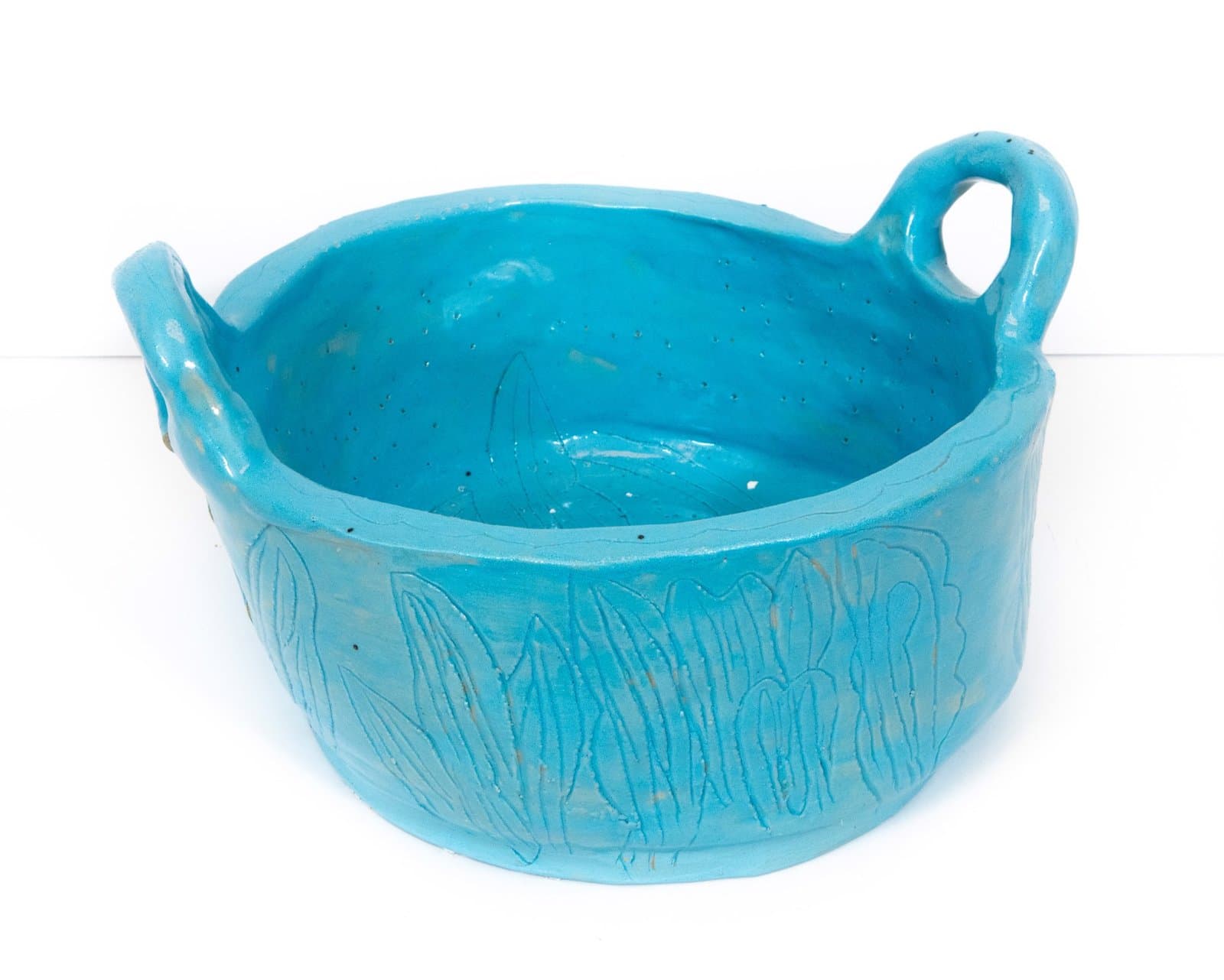 Turquoise ceramic bowl with two handles and carved linear patterns around the exterior walls