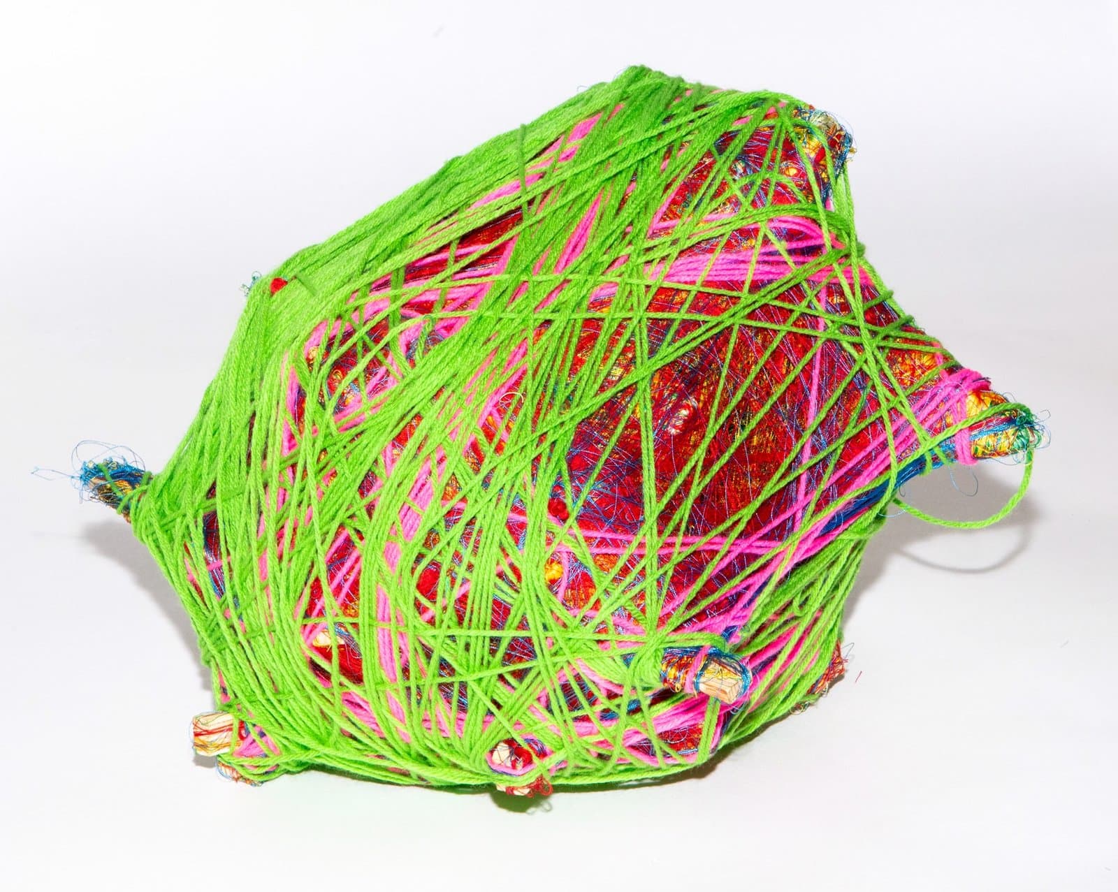 Fiber sculpture with bright green yarn wrapped around colorful core materials including pink, red, and multicolored threads.