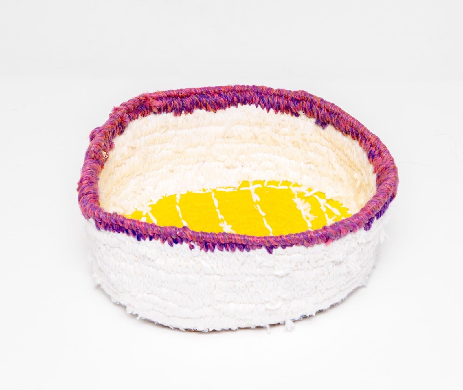 Coiled basket with purple and pink rim, white body, and bright yellow geometric pattern in center