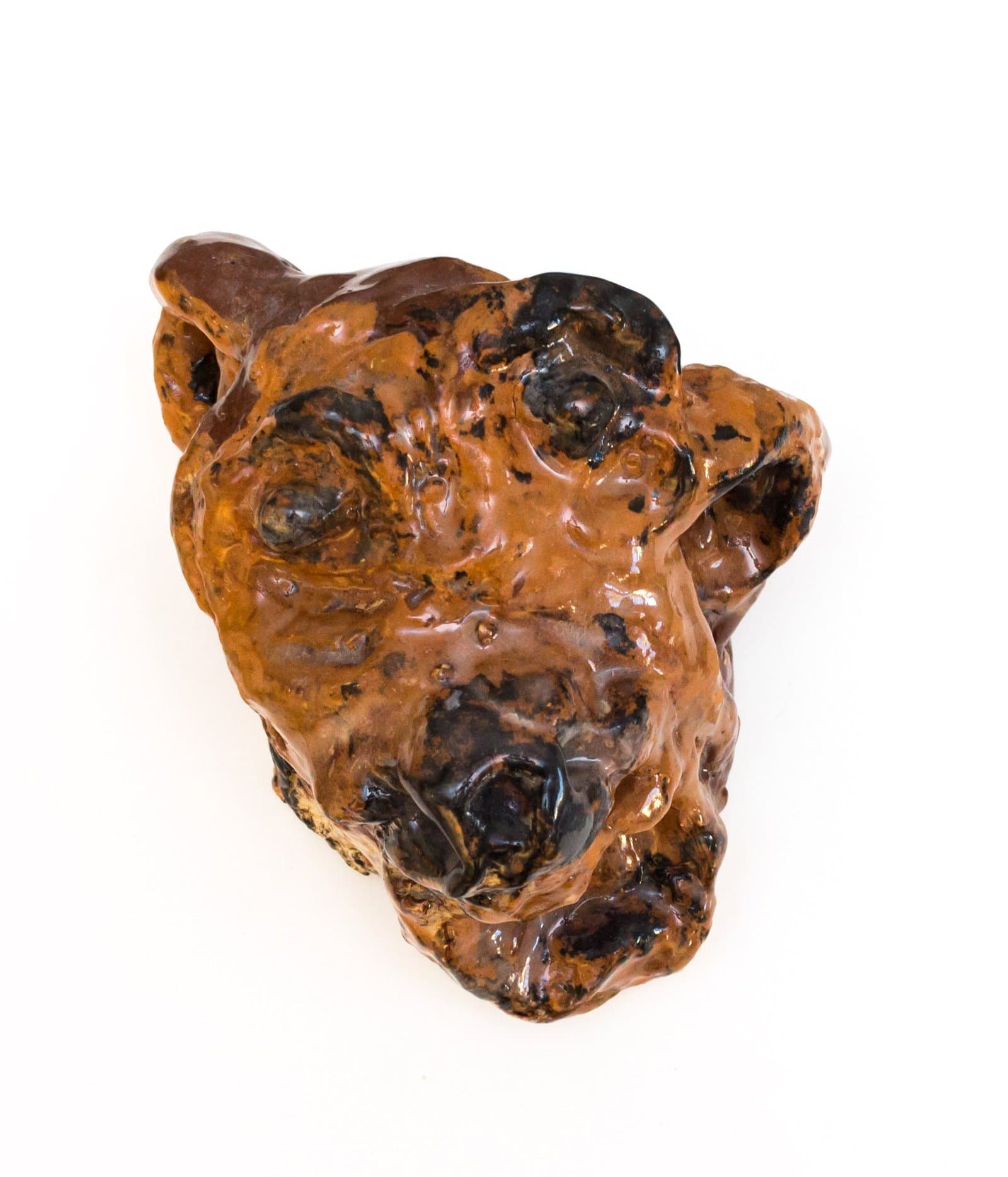 Sculptural ceramic vessel resembling an animal head with glossy amber and dark brown glazed surface