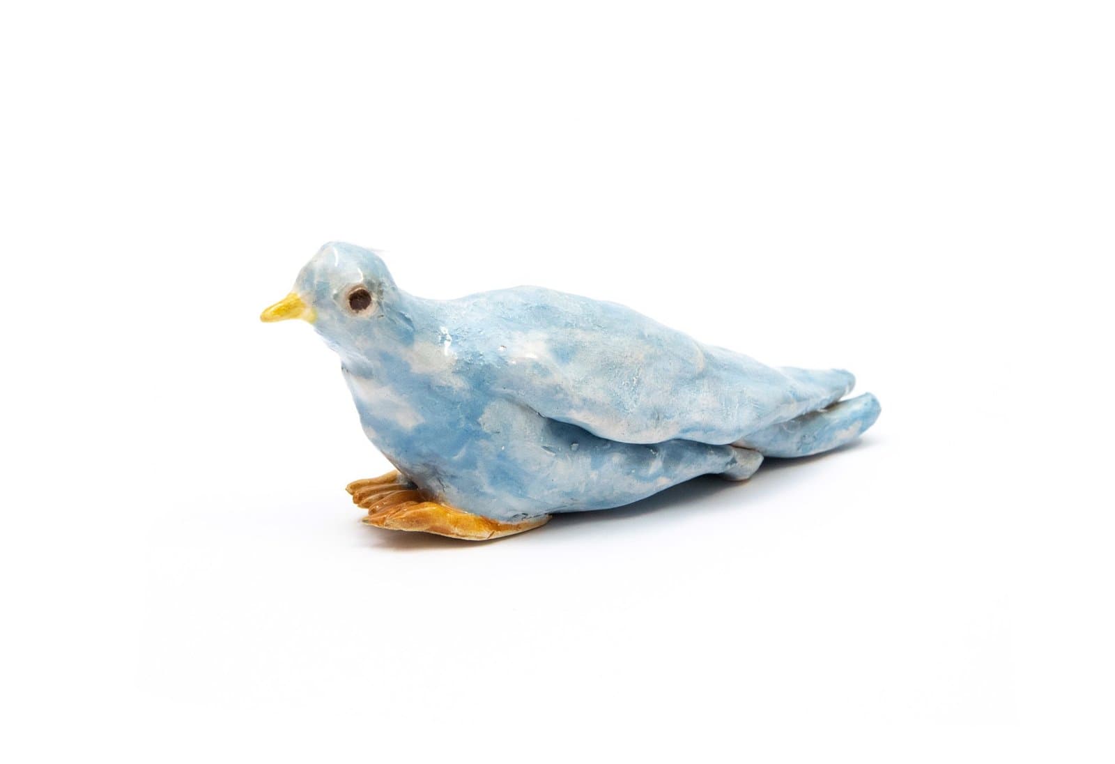 Ceramic sculpture of a blue bird with yellow beak and orange feet, glazed in mottled blue and white.