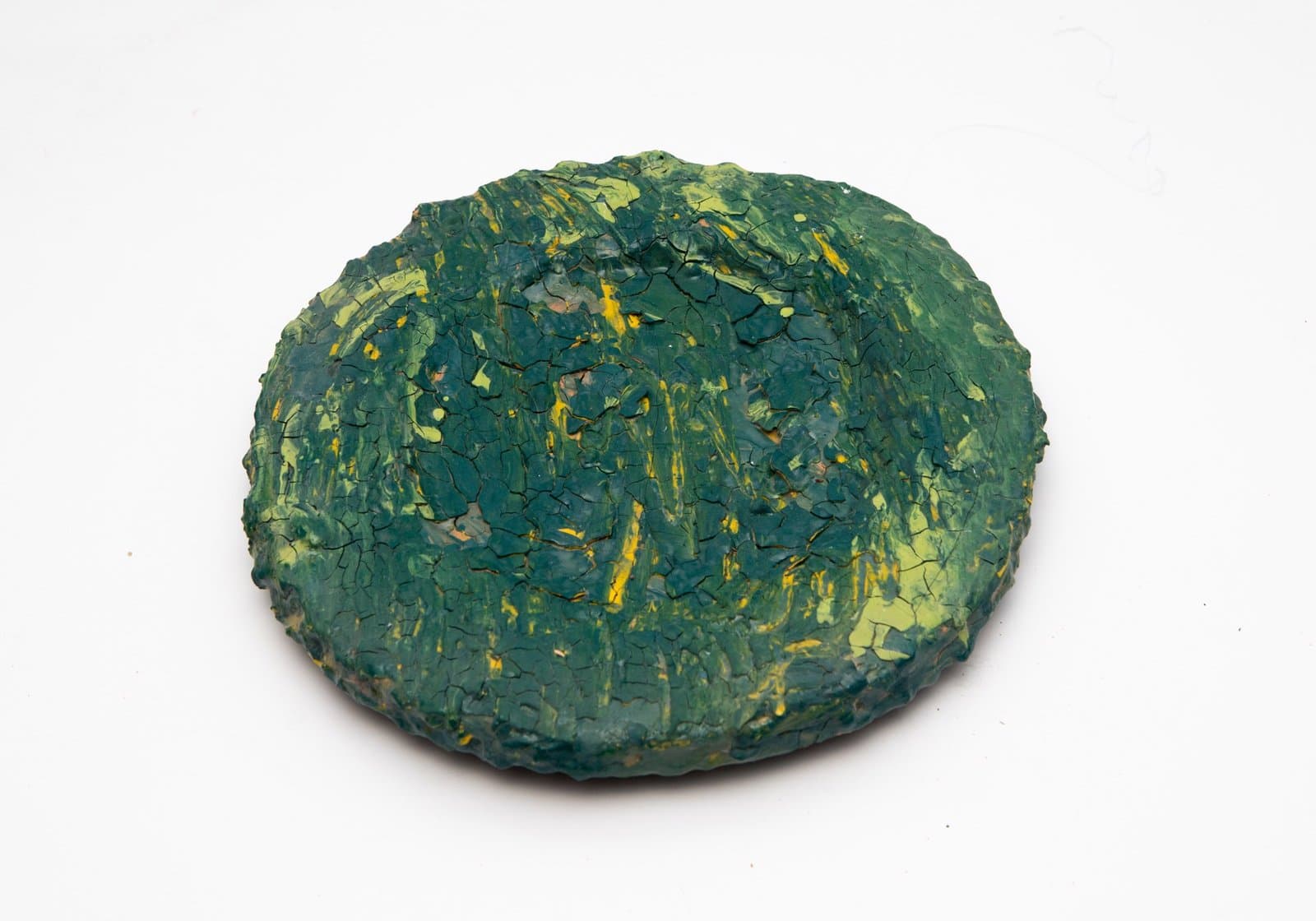 Ceramic bowl with heavily textured surface in dark green and yellow glazes with crackled finish.